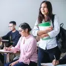 woman carrying white and green textbook