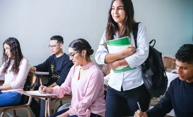 woman carrying white and green textbook